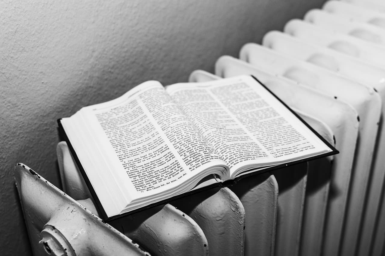 An open book resting on a white column radiator