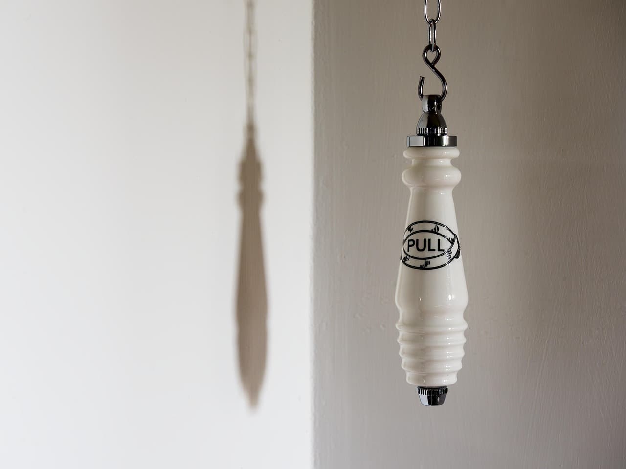 The porcelain pull handle of an old high-level cistern on its chain