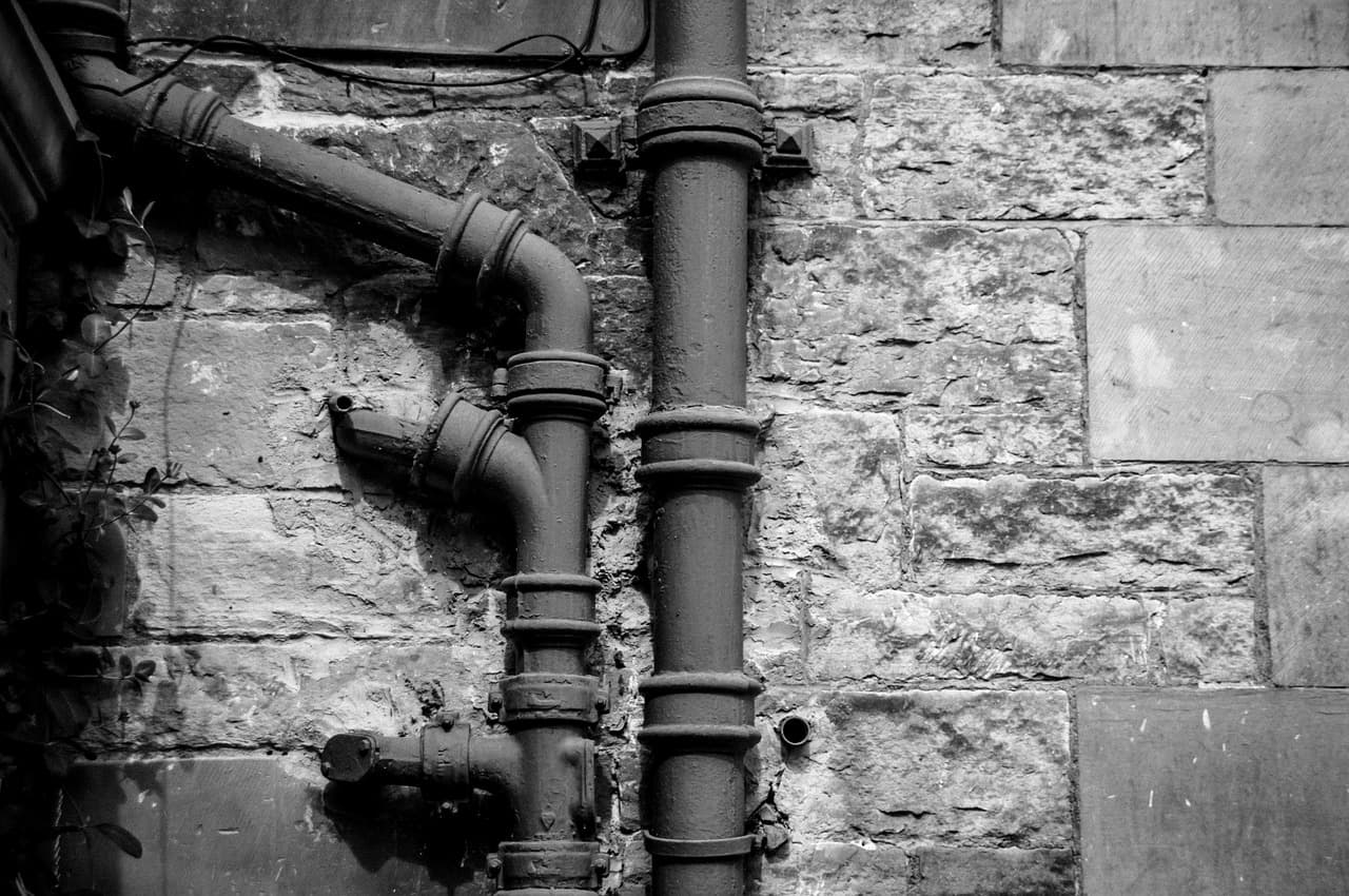 A cast-iron downpipe and its joints on an old stone wall